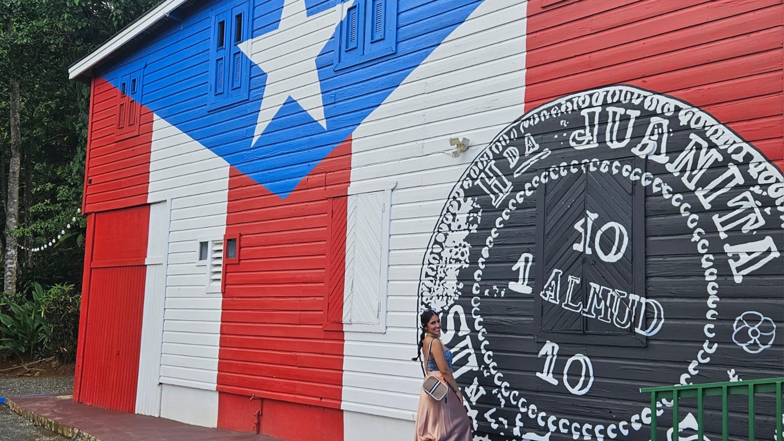 Paola Medina López with a mural of the Puerto Rican flag in background.