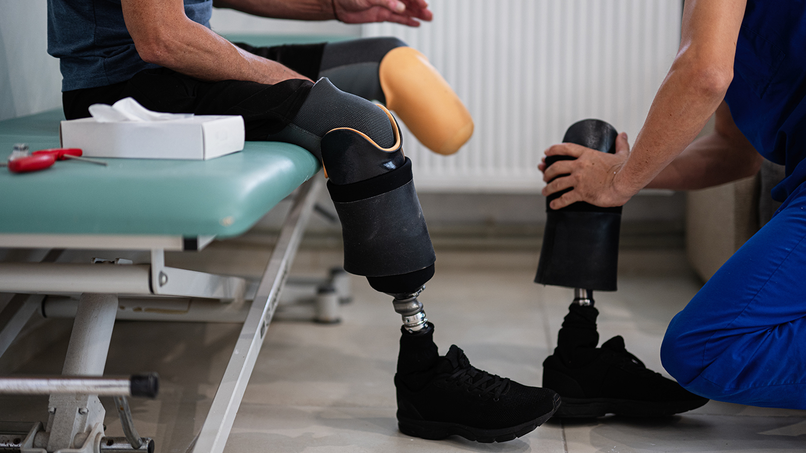 A healthcare provider assists a patient with the fitting of prosthetics.