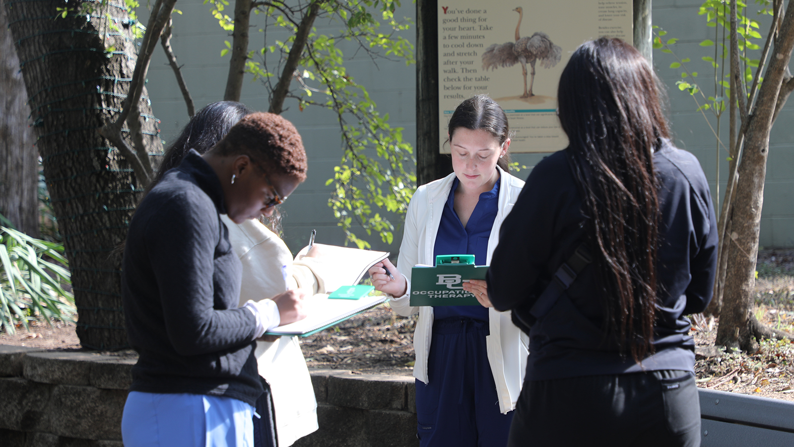 Baylor OTD students write notes on their clipboards as they evaluate a zoo environment. 