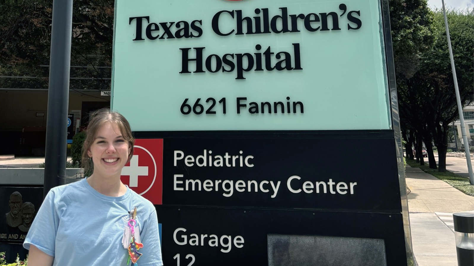 Harper Dorris stands in front the Texas Children's Hospital sign for its Pediatric Emergency Center