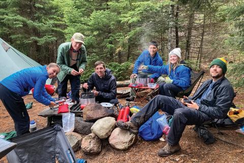 Six Baylor students huddle around a campfire to cook their dinner, while camping in the Appalachian Mountains.