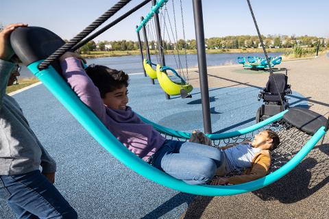 A crescent-shaped swing that provides a comfortable full body swinging experience and allows individuals using mobility devices to be easily transferred into the swing and supported.