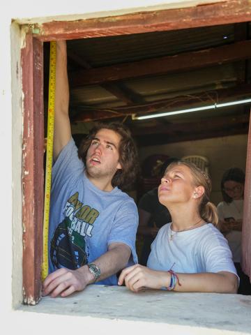 Baylor Interior Design students use a tape measure on a window at Iglesia Bautista Luz de Vida in Bárcena, Guatemala.