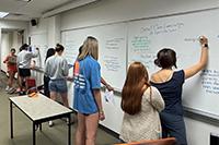 Students write on a classroom whiteboard during discussion during their "Religion and Sport" course.