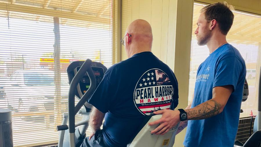 Baylor DPT student guides a client working out on a stationary bike.