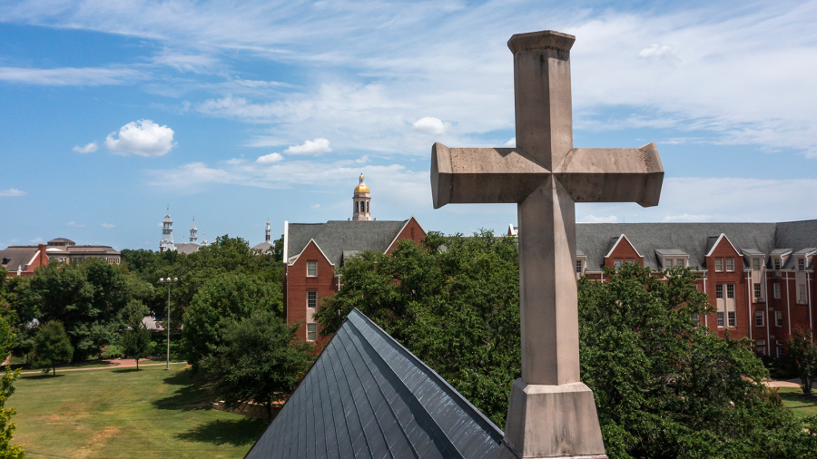 A concrete cross atop a building, with Baylor University campus in the background.