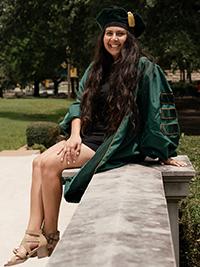 Portrait of Anjelica Elizondo, wearing her PhD graduation cap and gown. 
