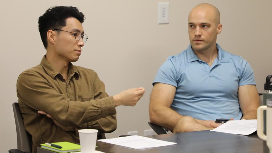 Two men engaged in discussion while sitting at a table. 