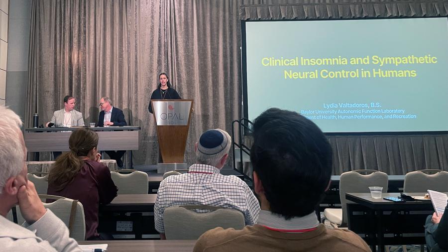 Lydia Valtadoros stands at a podium to present her findings at a national conference. 